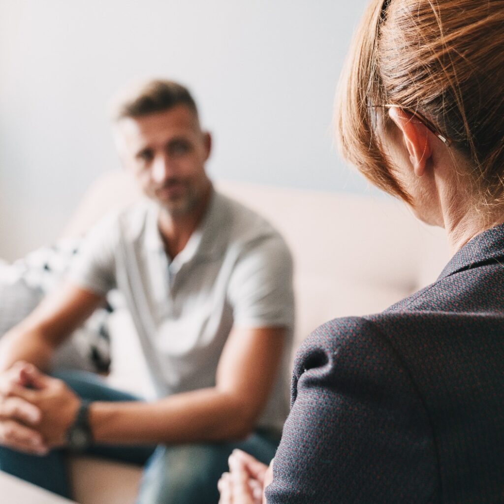 Foto eines kaukasischen Mannes im Gespräch mit einem Psychologen im Zimmer